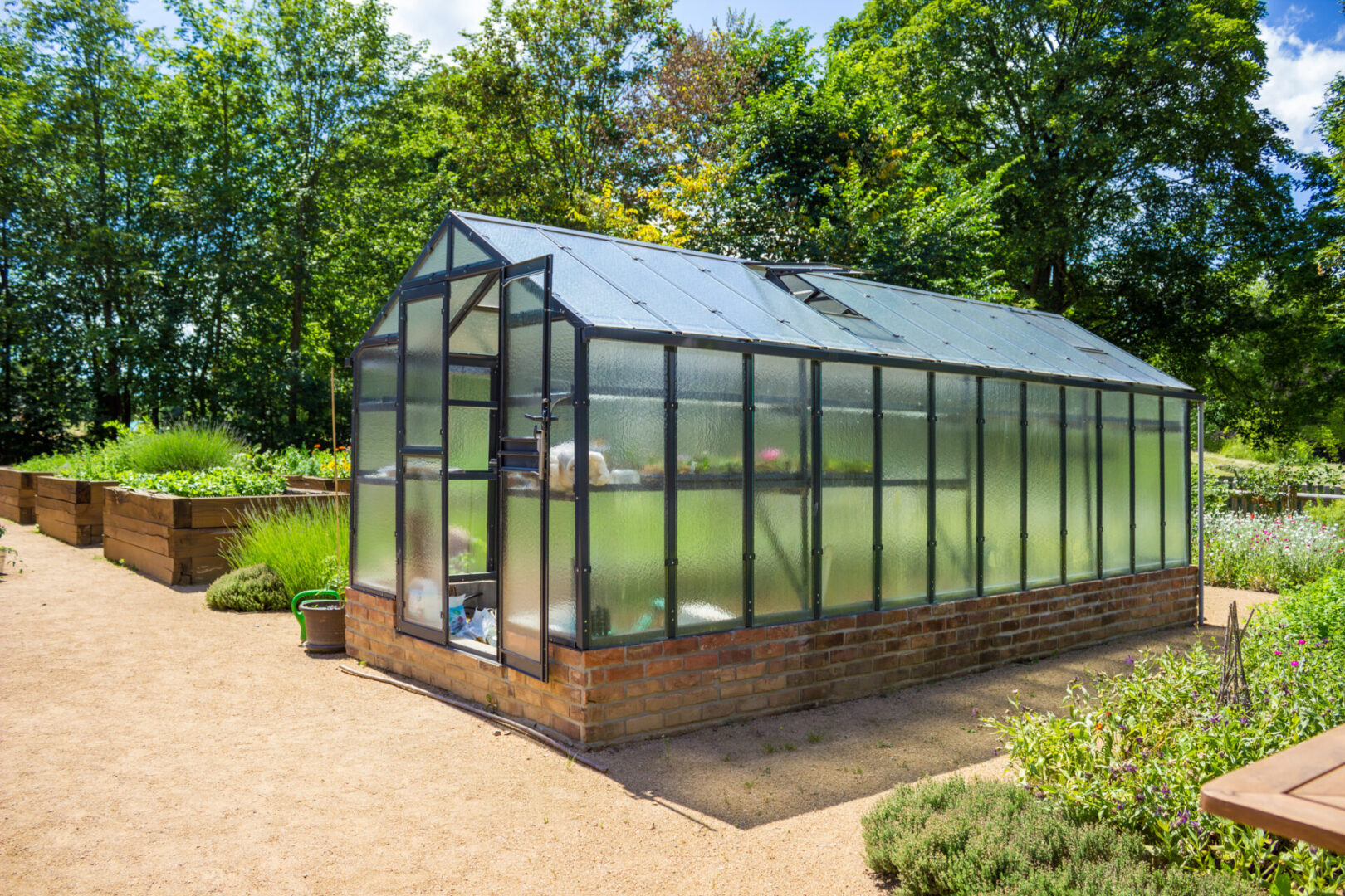 Garden with modern glass greenhouse
